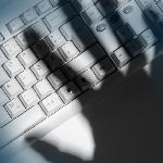 shadow of hand on computer keyboard